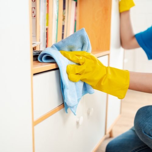 Careful dusting of shelves during a home cleaning